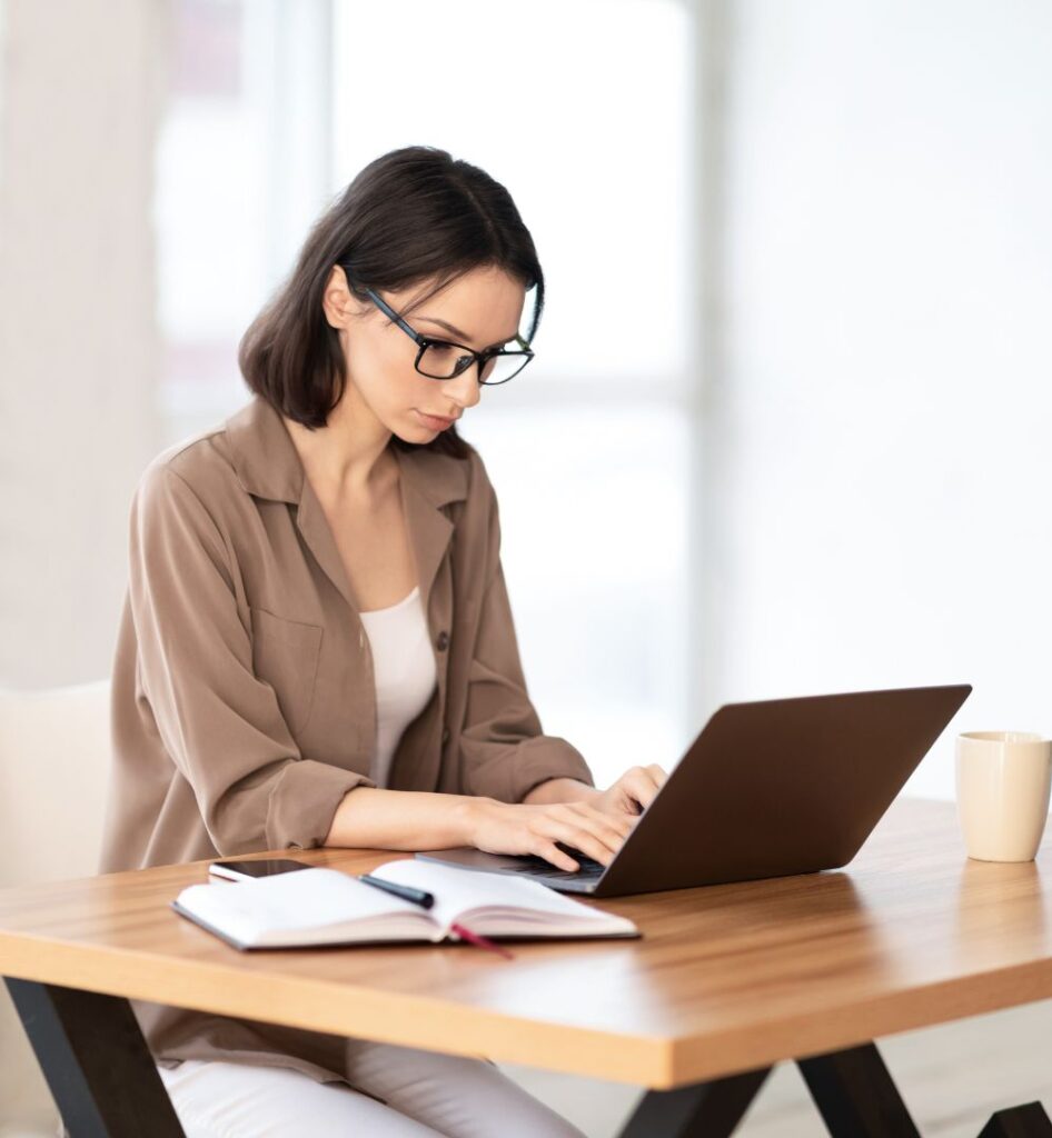 Woman Sitting At A Table Using A Laptop